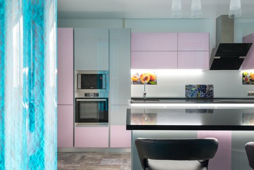 Free Black kitchen counter with chairs placed near colorful cupboards and contemporary appliances in stylish apartment with decorative blue bubble wall Stock Photo