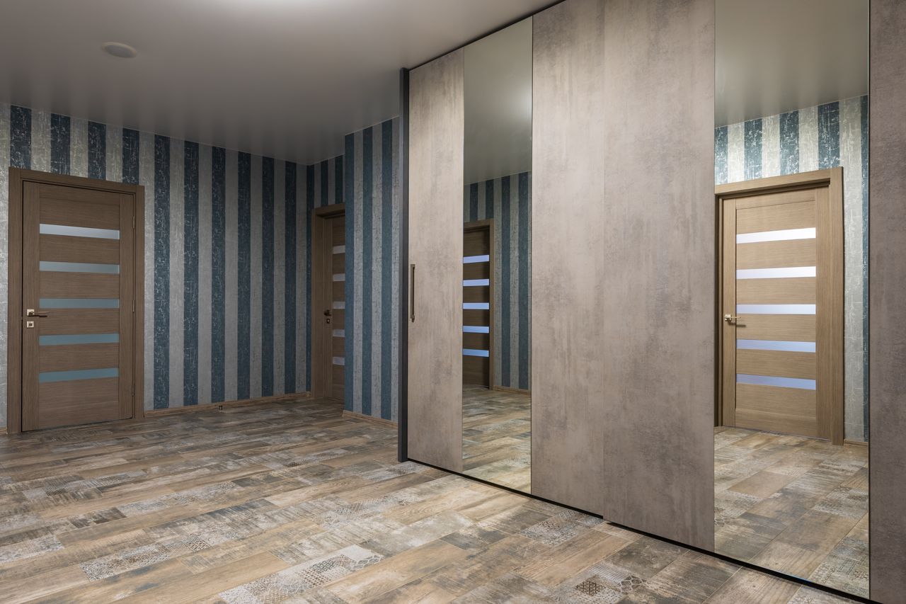 Entrance area with patterned wood-look floor tiles and a mirrored wardrobe