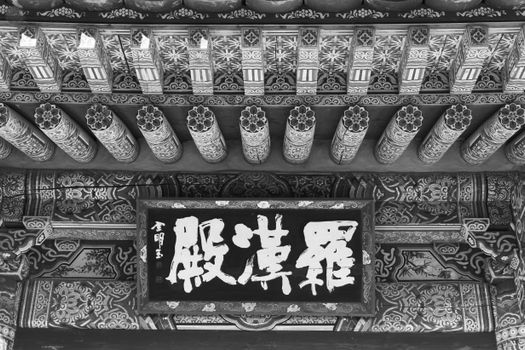 Black and white photo of ornate traditional Chinese architecture with intricate patterns and calligraphy.
