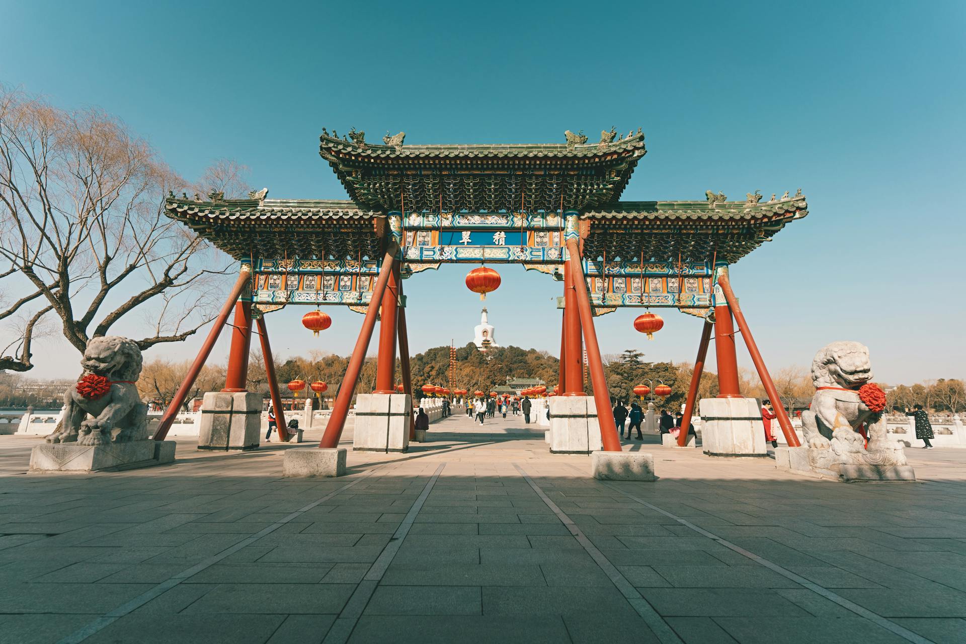 Scenic view of a traditional Chinese gateway adorned with red lanterns against a clear sky.