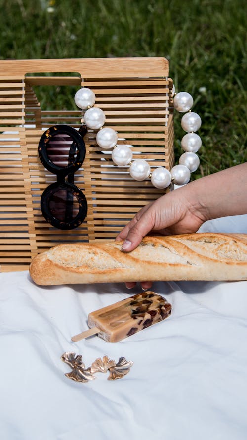 Hand Holding Baguette at Picnic
