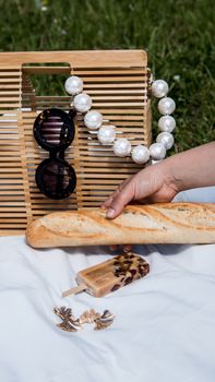 A stylish summer picnic scene with baguette, ice cream, sunglasses, and accessories.
