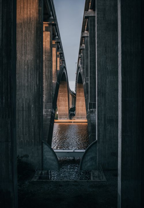 Free A captivating underbridge view in Stockholm with imposing concrete structures reflected in water. Stock Photo