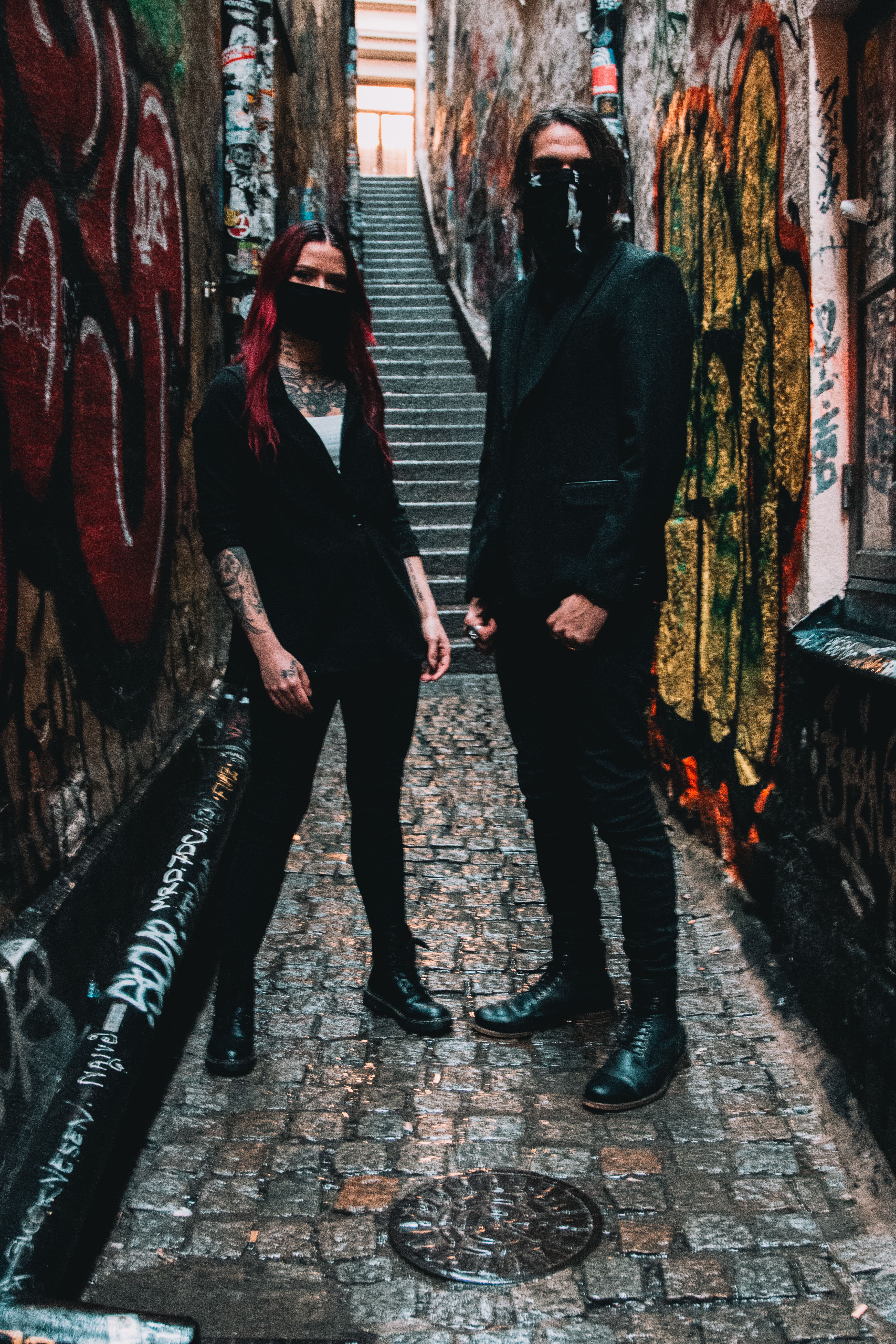 A stylishly masked couple in Stockholm's colorful graffiti alleyway.