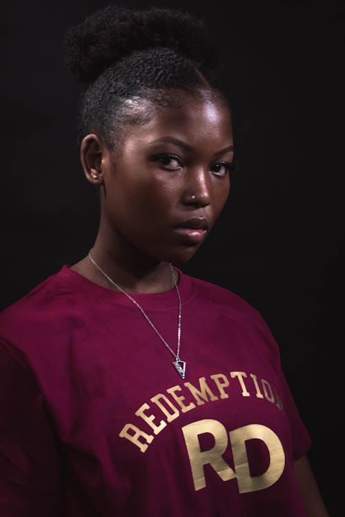 A Woman in Red Shirt Wearing Silver Necklace while Looking with a Serious Face