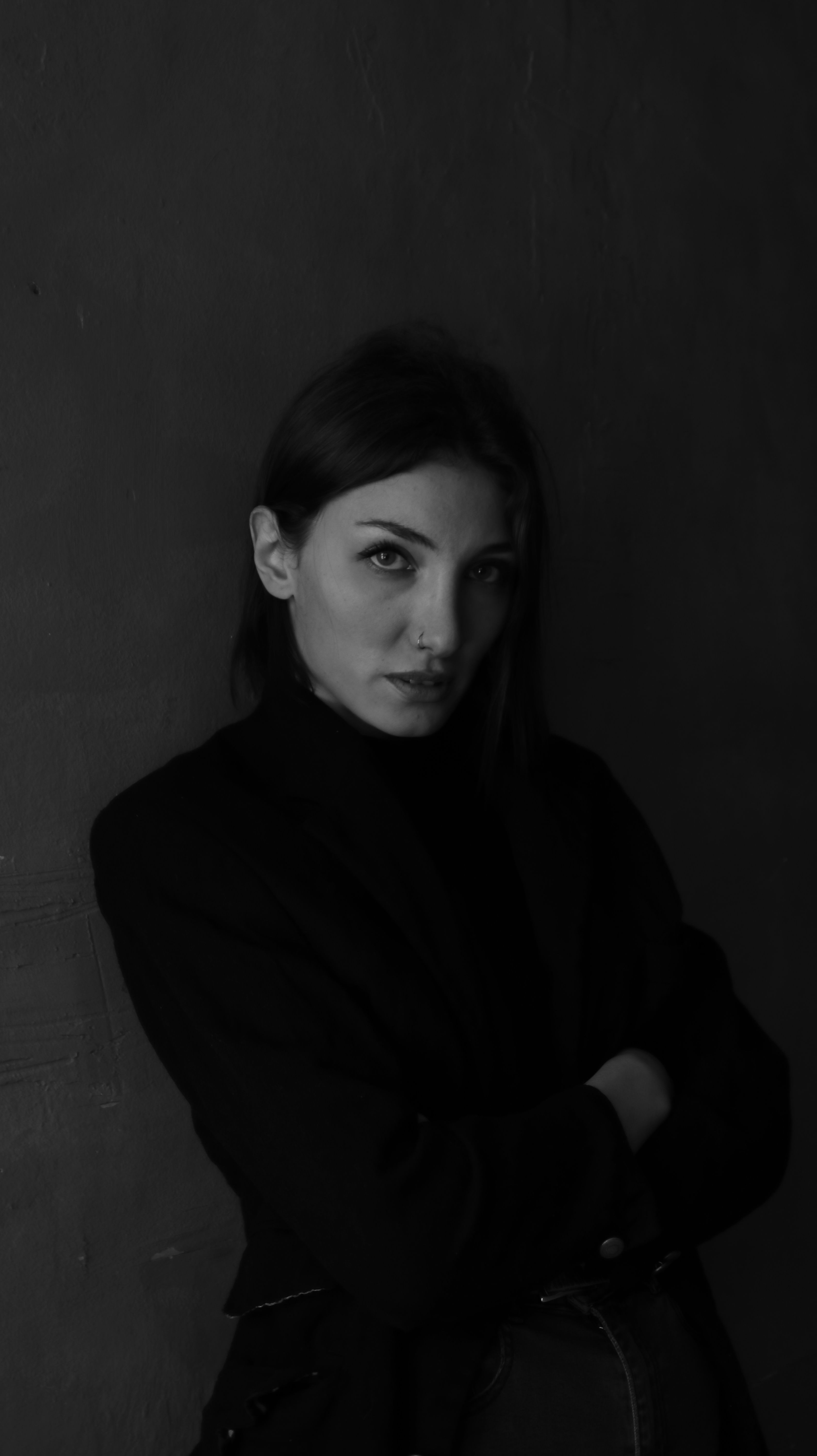Portrait of a woman in a dark setting, showcasing a contemplative expression in black and white.