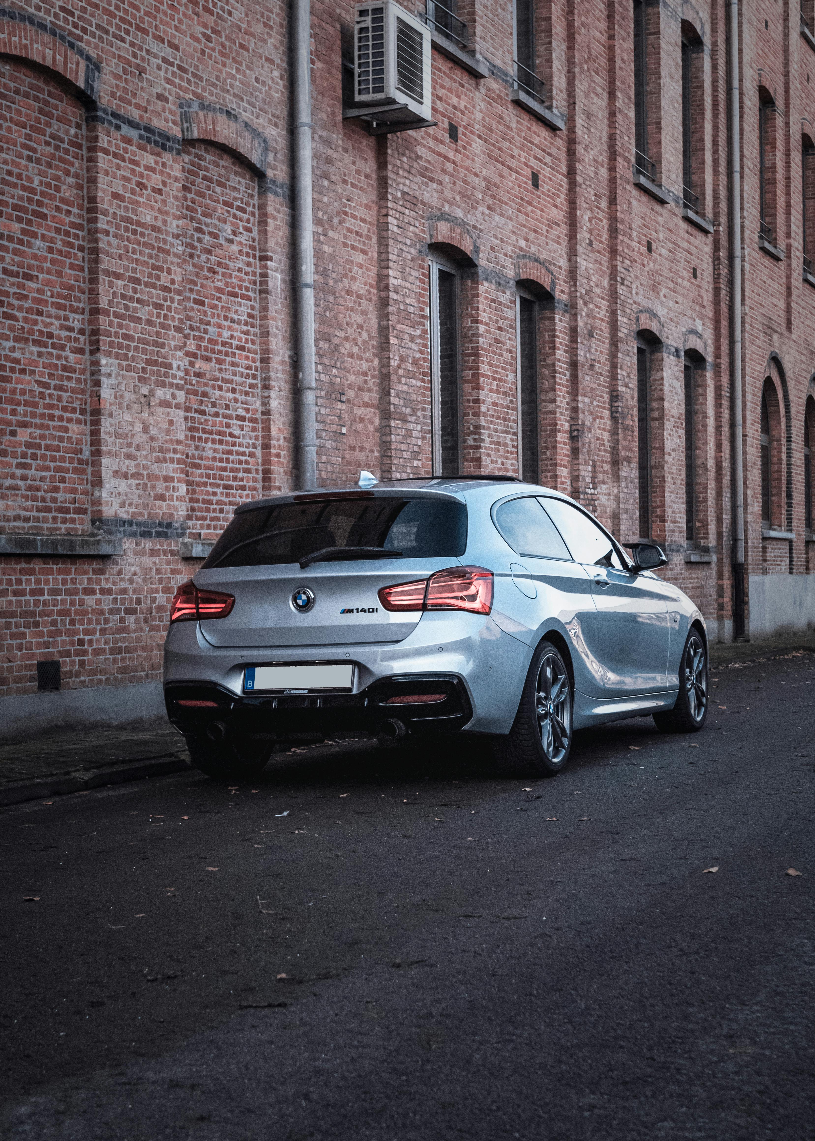 Free Stylish silver car parked on urban street against a brick wall. Ideal for transportation imagery. Stock Photo