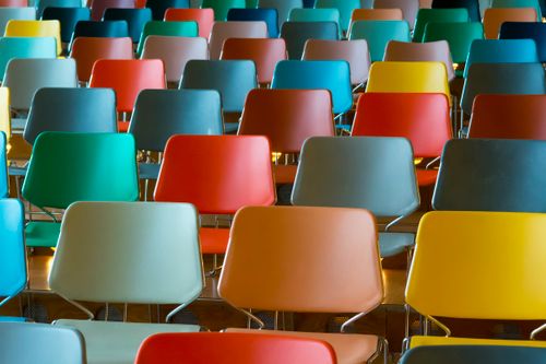 Free A vibrant array of colorful empty chairs arranged in rows inside an auditorium. Stock Photo