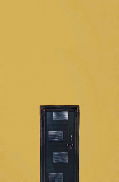 Free Black door on a large yellow wall offering ample copy space. Stock Photo