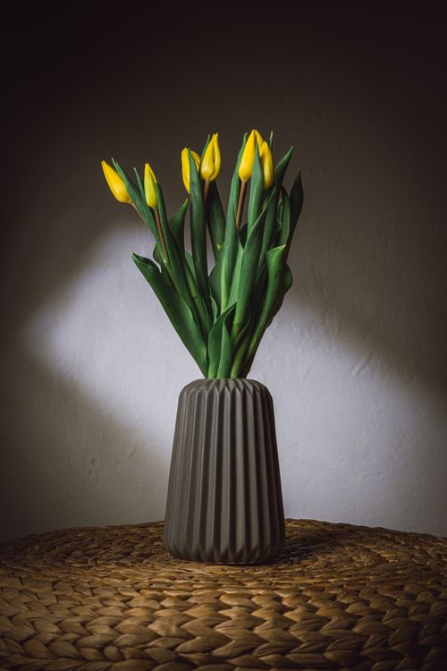 Free Yellow tulips arranged in a textured vase against a dark background, perfect for floral decor inspiration. Stock Photo