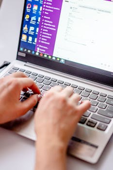 From above of crop anonymous female freelancing with netbook while using keyboard at table