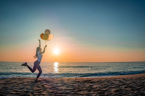 Free A Woman Holding Balloons at the Beach  Stock Photo