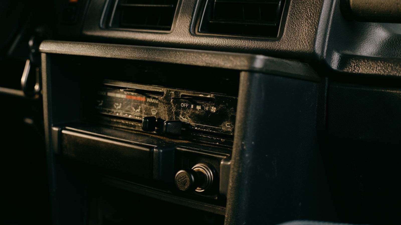 Close-up of the dials and knobs on an old car's dashboard radio, a real photo chosen for GTA 6's in-game radio stations, with no people in the frame