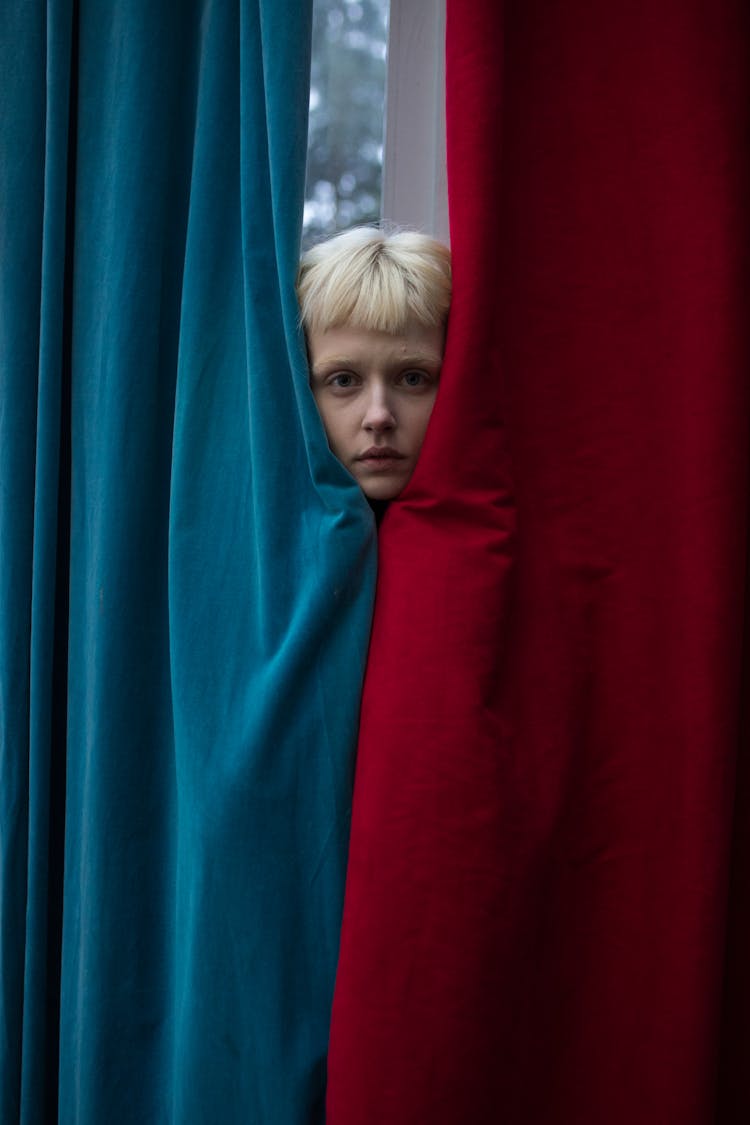 A Woman Behind A Red And Blue Curtains