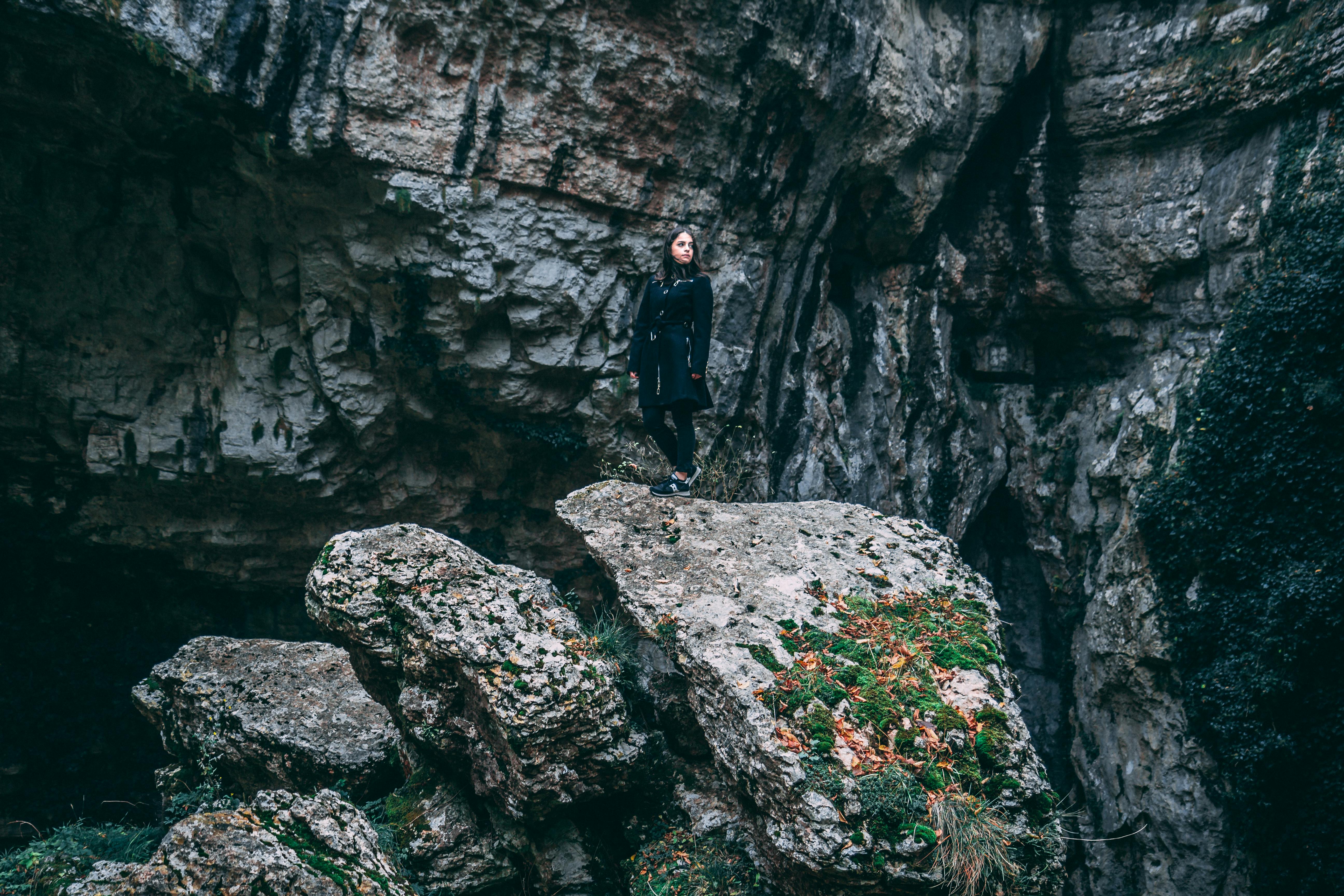 A woman exploring rocky terrain in Sant'Anna D'alfaedo, Veneto, Italy, showcasing natural cliffs.
