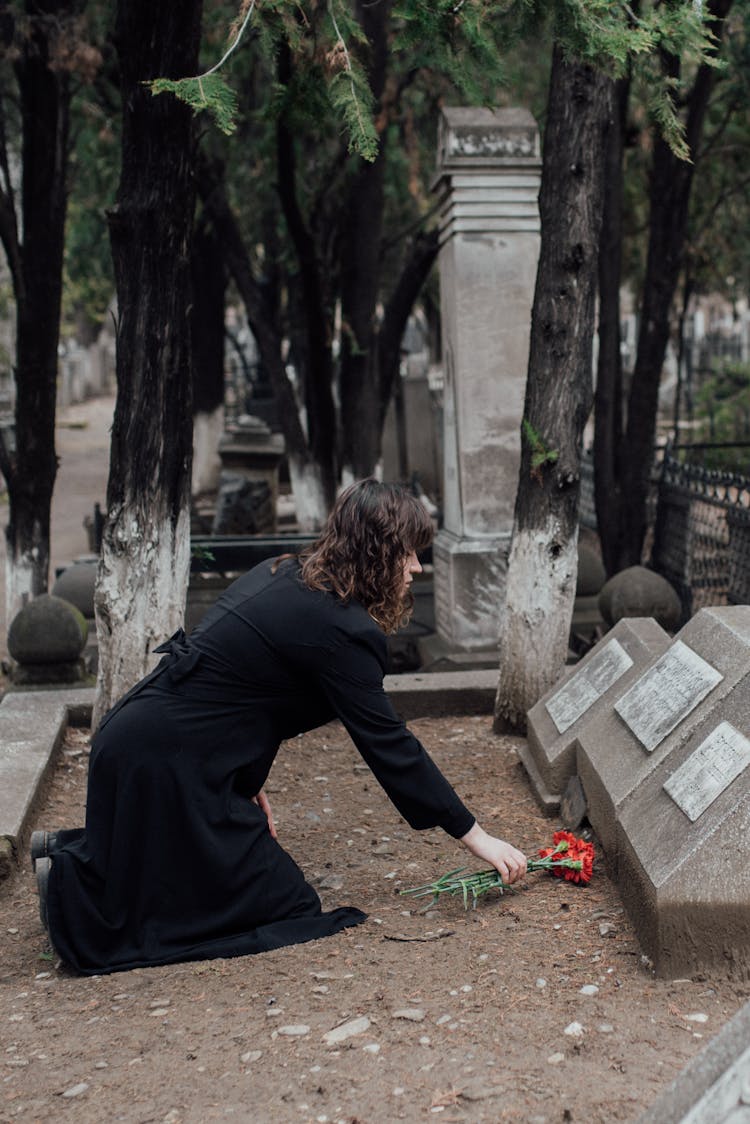 A Woman Offering Flowers On A Grave