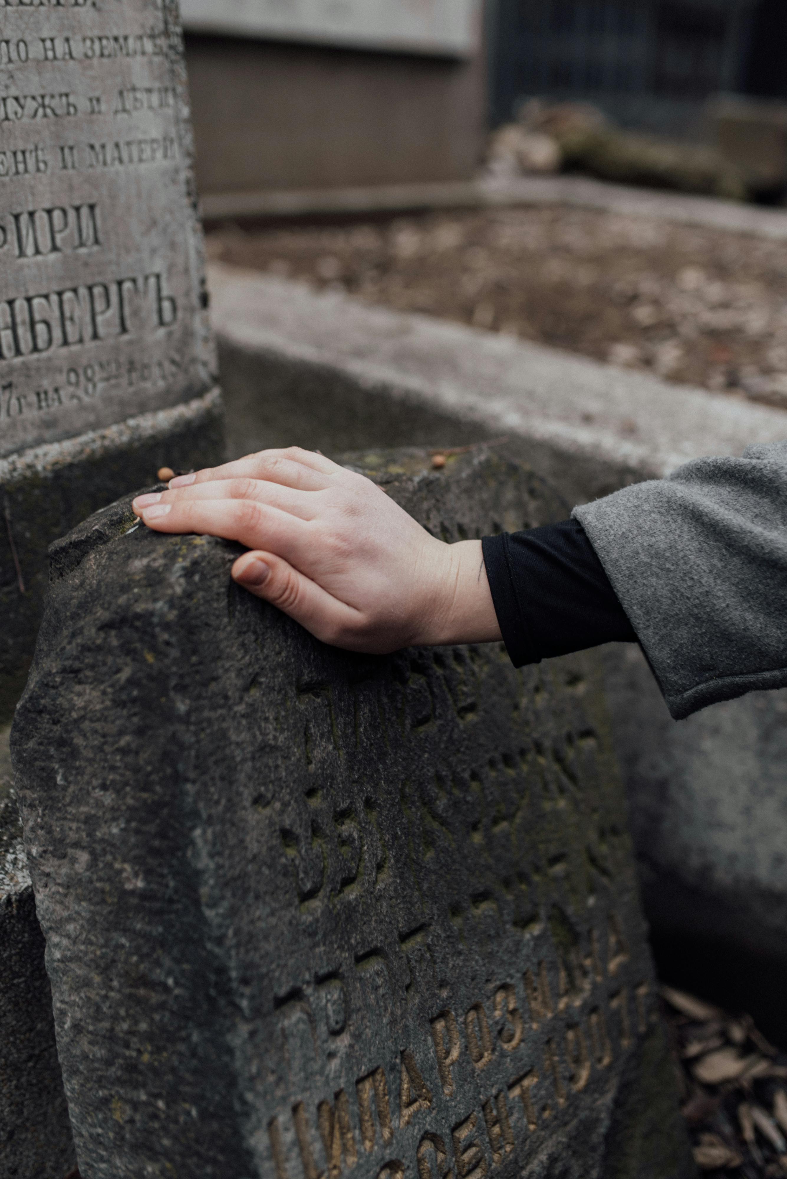 photo of a hand on an old grave stone