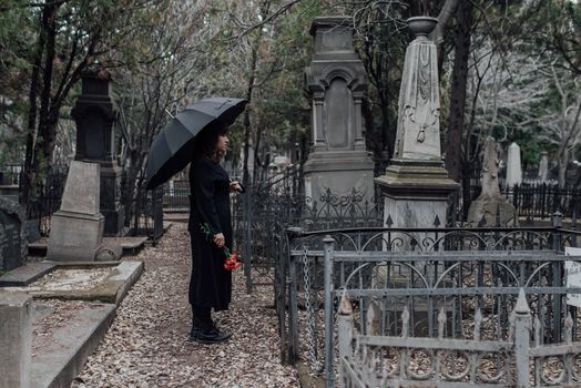 Woman in Black Coat Holding Umbrella Standing Near Grey Concrete Statue