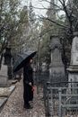 Woman in Black Coat Holding Umbrella Standing Near Statue