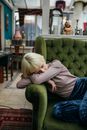 Photo of a Woman with Blue Pants Sitting on a Green Sofa