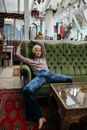 Girl in Gray Long Sleeve Shirt and Blue Denim Jeans Sitting on Green Sofa