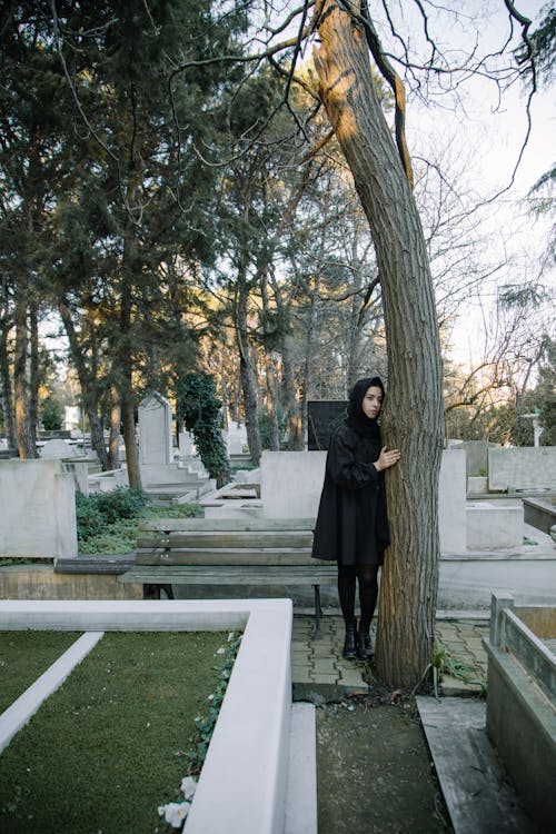 Upset woman in black outfit standing in cemetery