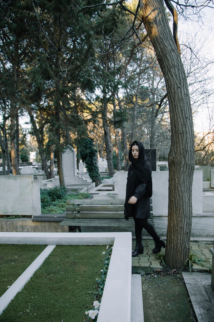 Sad Woman Walking In Cemetery In Daylight