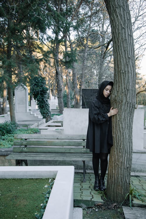Upset woman standing in cemetery in daylight