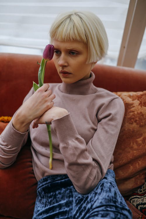 A Woman Holding a Flower while Sitting on the Couch