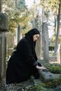 Woman in black wear sorrowing about dead in graveyard