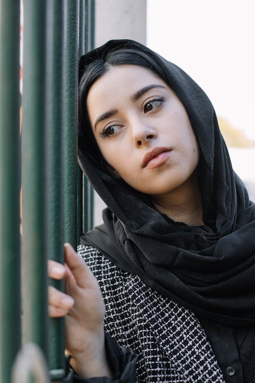 Serious woman in headscarf near fence
