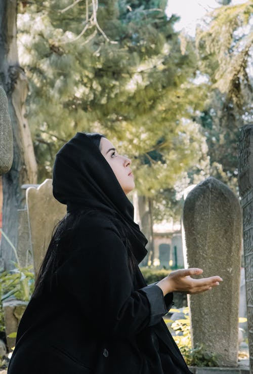 Ethnic woman praying on cemetery