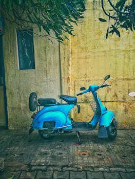 A classic blue scooter parked in an alley in Bengaluru, India, exuding a nostalgic and urban vibe.