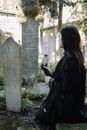 Woman sitting cemetery with gravestones