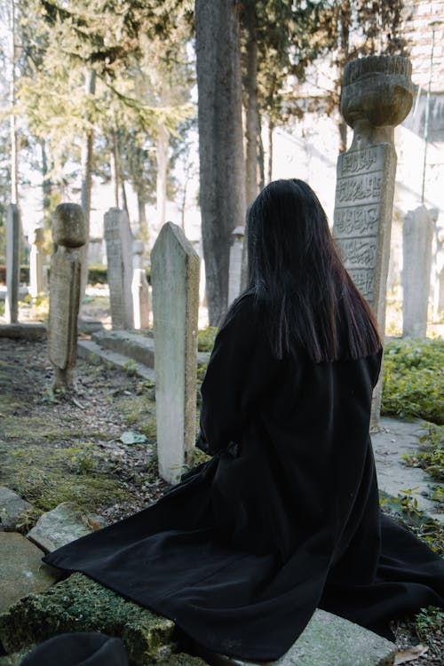 Unrecognizable woman sitting on cemetery