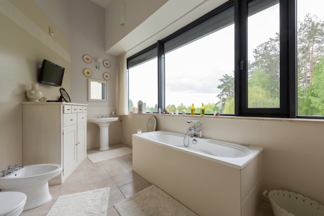 Interior of modern bathroom with bath near window
