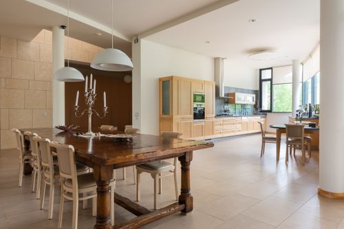 Free Wooden dining table with candlestick and chairs placed near kitchen counter with cupboards placed near window in stylish spacious apartment Stock Photo