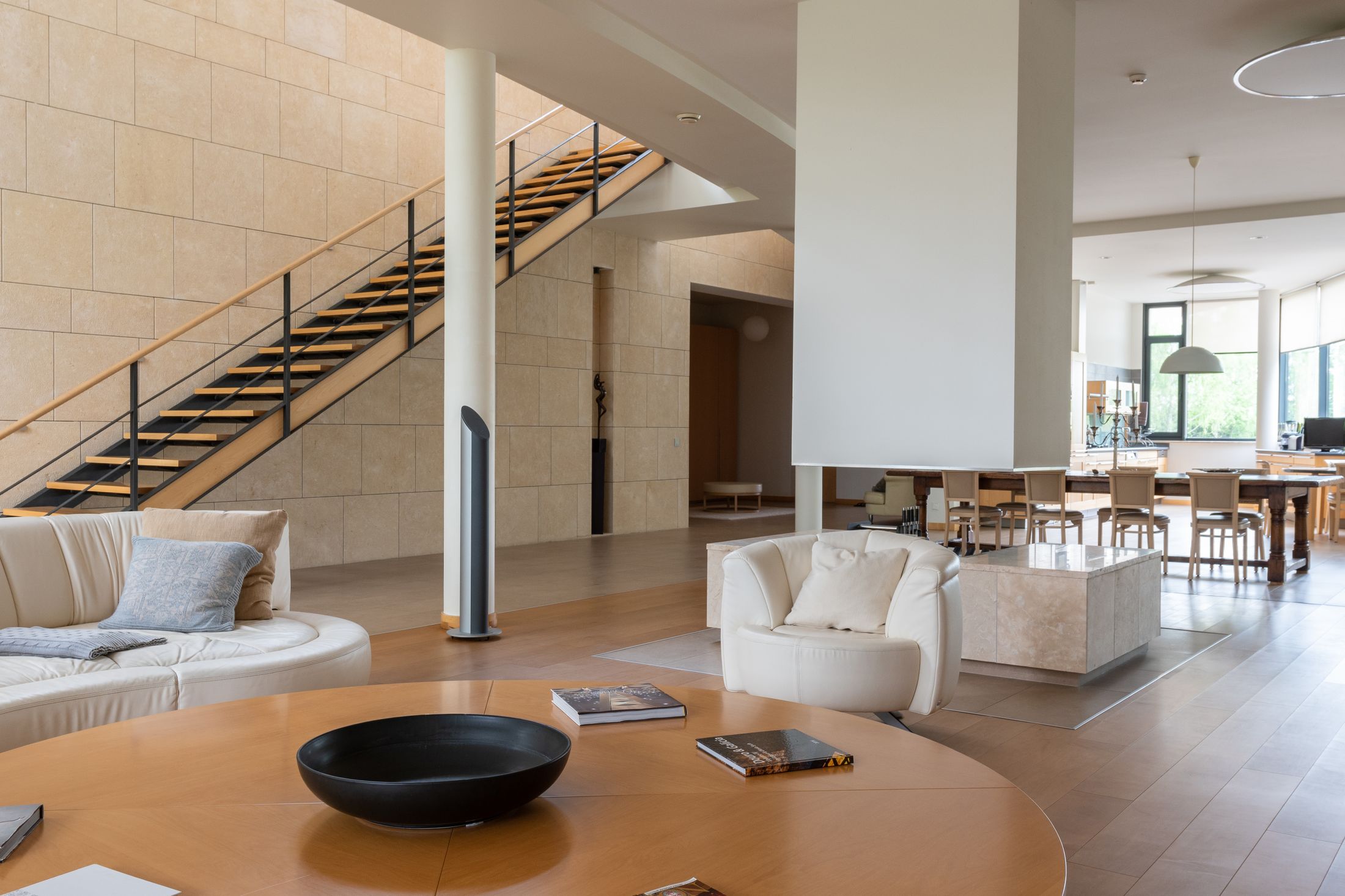 Spacious remodeled living room with modern staircase, large windows and refined interior finishes