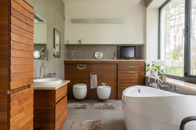 Bathroom With Wooden Furniture And Clean White Bathtub