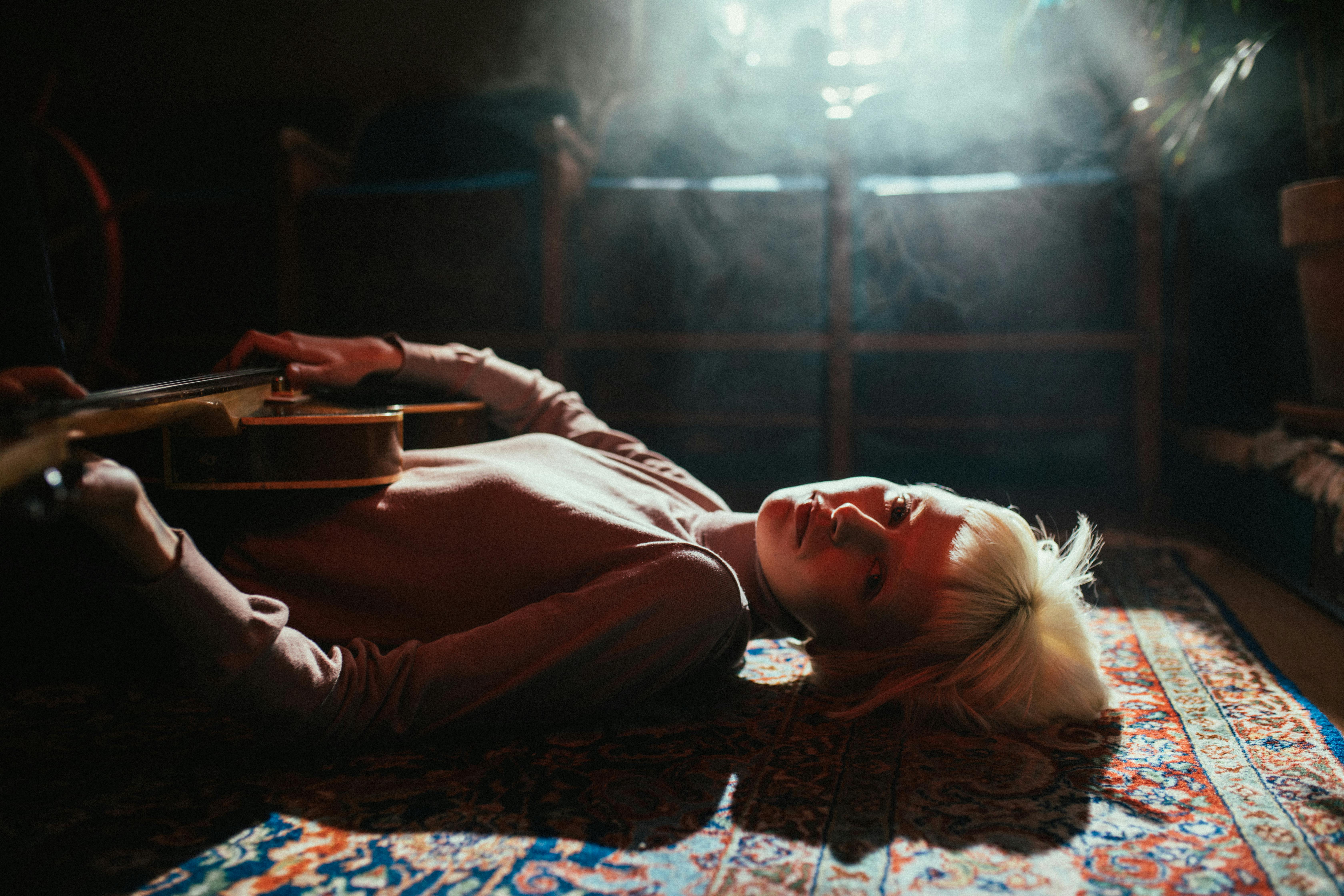 Woman in Pink Long Sleeve Shirt Lying on Bed