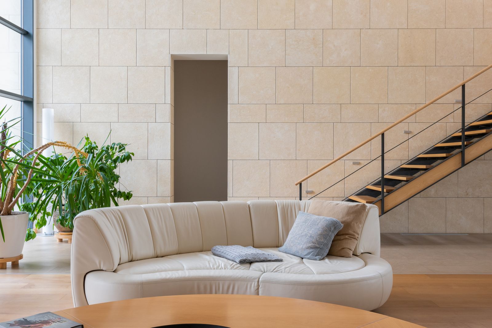 Curved cream sofa in a bright living room with plants and a stone wall