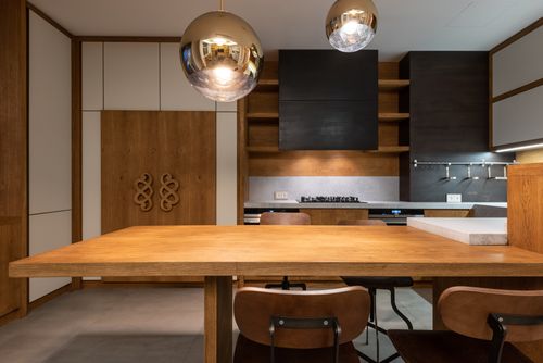 Free Sleek minimalist kitchen with wooden cabinetry and modern pendant lights. Stock Photo