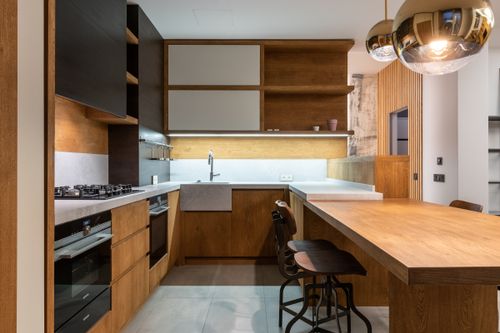 Free Sleek modern kitchen with wooden cabinets and pendant lamps. Stock Photo