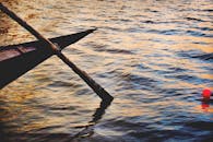 日落时分，一艘木制划艇静静地停在水面上，倒影在波光粼粼的水中显得格外生动