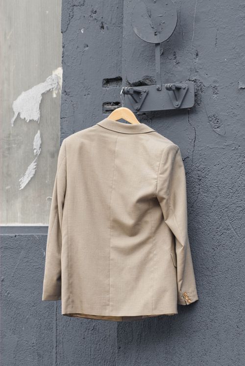 Free A tan jacket hangs on a textured urban wall, showcasing city style. Stock Photo