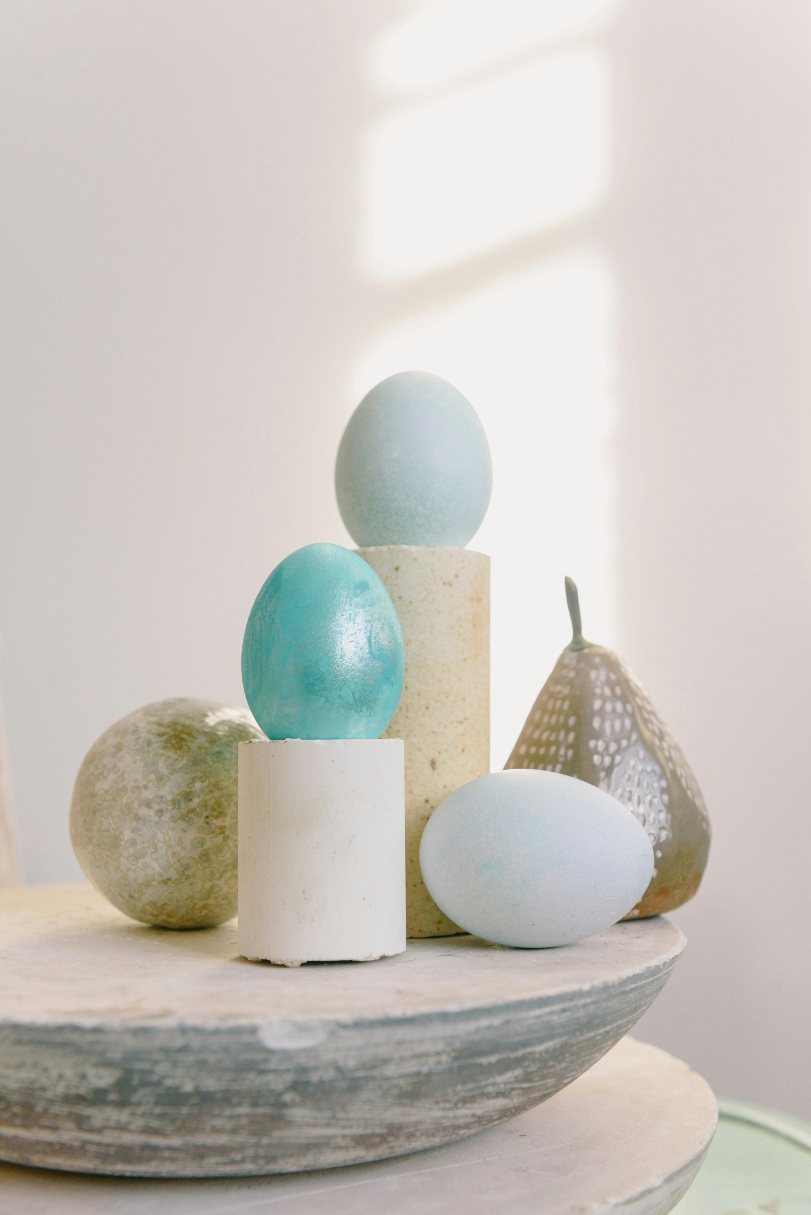 A minimalist composition featuring pastel-colored eggs and artistic objects in soft natural light.