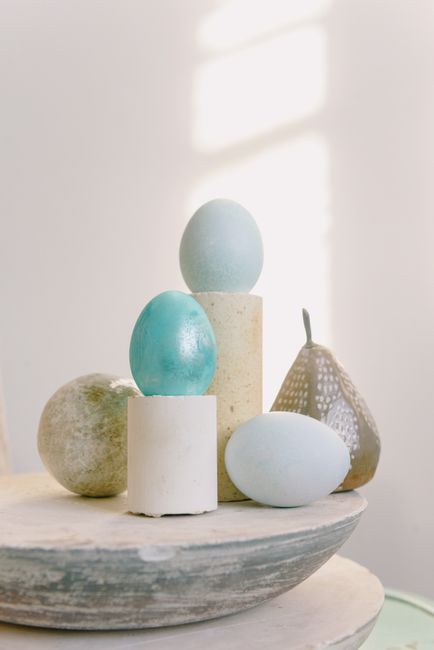 A minimalist composition featuring pastel-colored eggs and artistic objects in soft natural light.