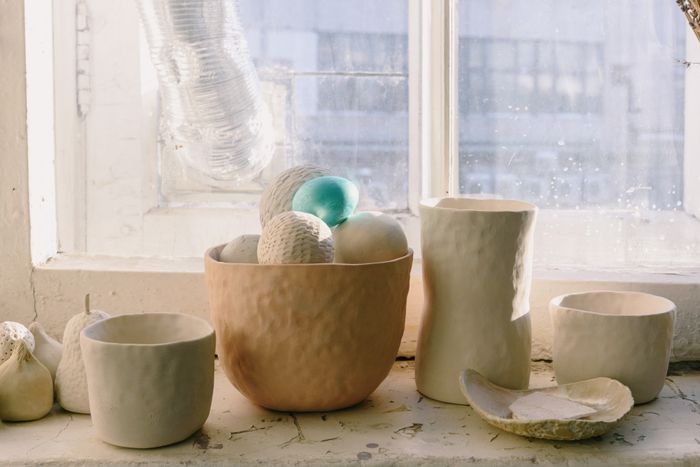 Unfired clay bowls and vases resting on a studio windowsill
