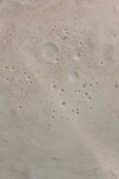 Abstract close-up of a concrete surface featuring bubble patterns and textures.