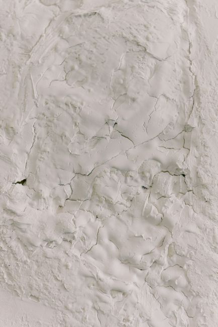 Detailed close-up of white cracked plaster texture, ideal for backgrounds.